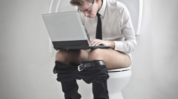 Ung mand på toilet med computer